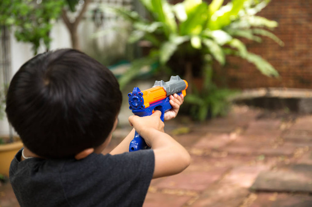 Μικρό αγόρι παίζει με ένα πυροβόλο όπλο παιχνιδιών  - Φωτογραφία, εικόνα