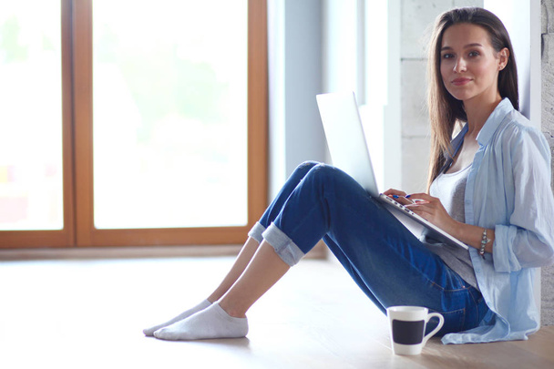 Young beautiful woman at home sitting on the floor with laptop. Young beautiful woman. - Fotoğraf, Görsel