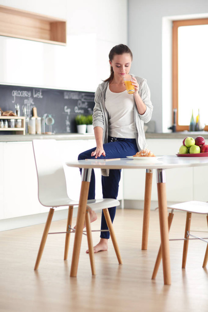 Young woman with orange juice and tablet in kitchen. - Foto, immagini