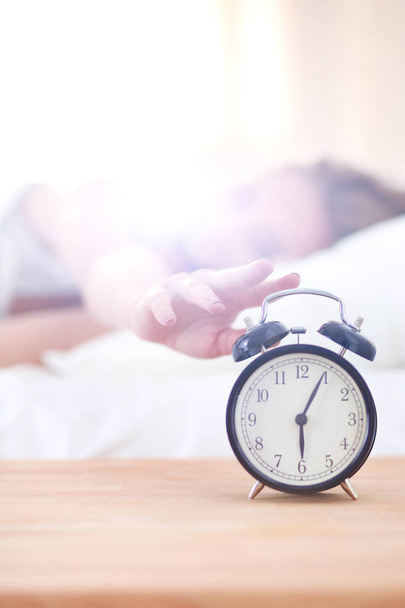 Young sleeping woman and alarm clock in bedroom at home. Young sleeping woman. - Фото, зображення