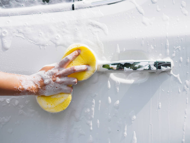 Γυναίκα χέρι με κίτρινο σφουγγάρι πλυσίματος αυτοκινήτων - Φωτογραφία, εικόνα