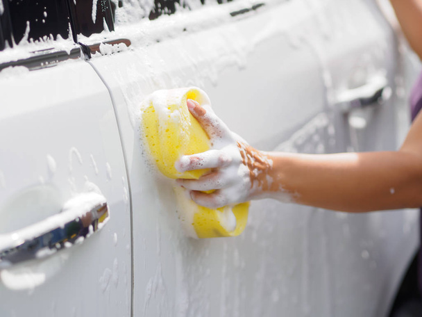 Woman hand with yellow sponge washing car - Foto, Imagem