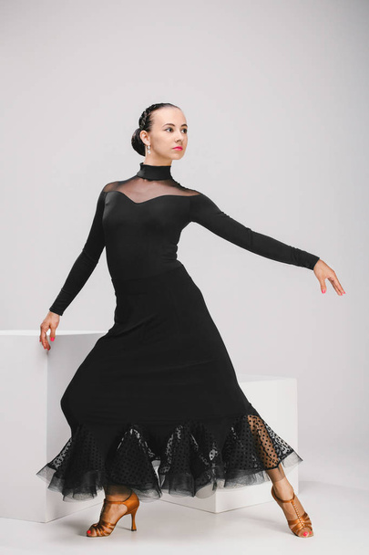 young woman in black dress dancing in studio - Fotografie, Obrázek