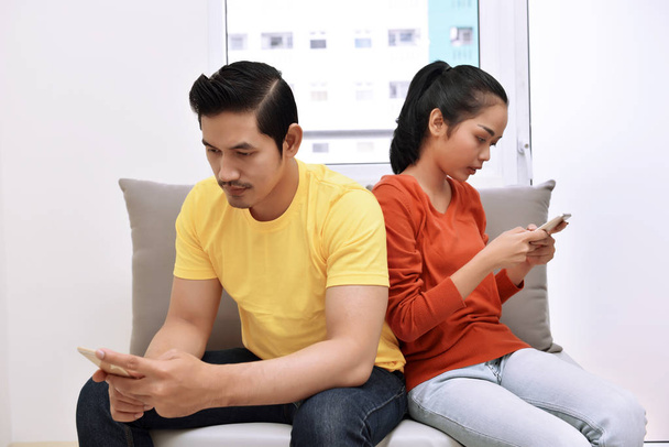 Asian couple sitting with mobile phones - Fotoğraf, Görsel