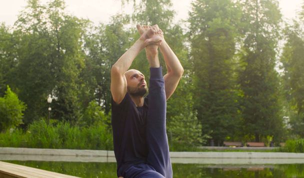 Ένας άνθρωπος που κάνει Γιόγκα ασκήσεις στο πάρκο - Φωτογραφία, εικόνα