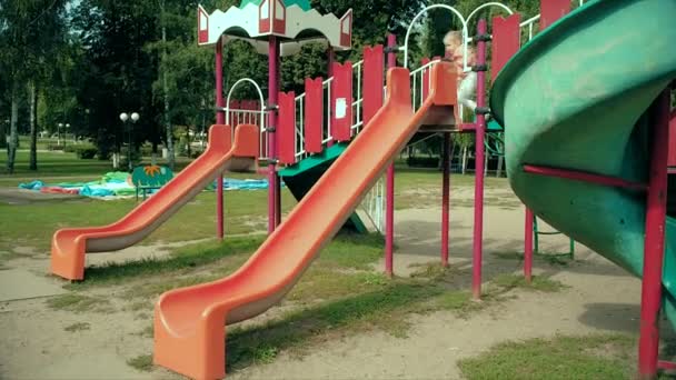 Niño deslizándose en una diapositiva en el parque, Niña jugando en el patio de recreo, Niños
 - Metraje, vídeo