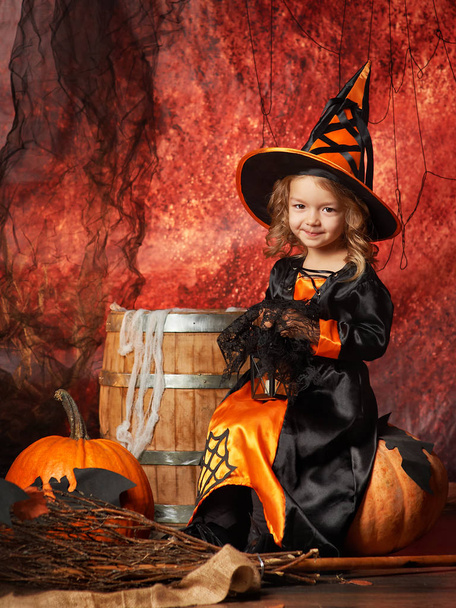 Happy Halloween! Cheerful little girl in a witch costume sitting - Foto, imagen