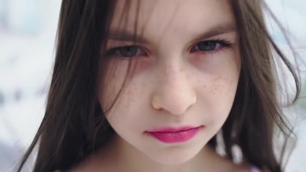 Portrait of a young girl with a tense glance at the camera. The wind disperses her hair. - Filmagem, Vídeo