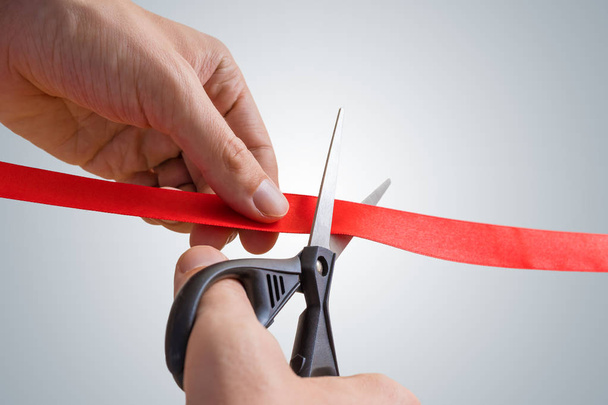 Man hands are cutting red ribbon with scissors. Opening event. - Photo, Image
