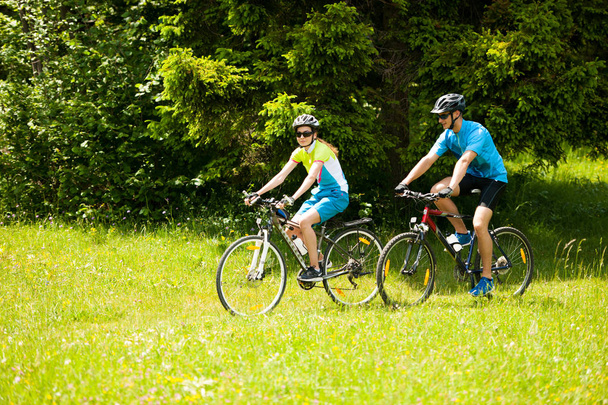 Bir spr dağda bir orman yolu üzerinde bisikleti aktif genç Çift - Fotoğraf, Görsel
