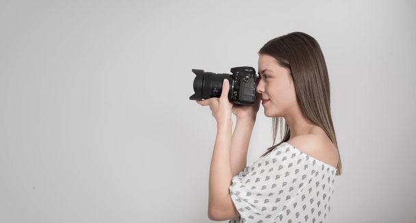 Woman photographer taking photograph against grey background - Foto, imagen