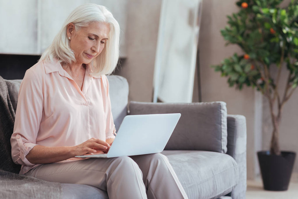 Nice aged woman using her laptop at home - Zdjęcie, obraz
