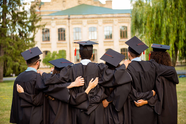 Back view of six successful graduates in black robes, bonding, i - Foto, imagen