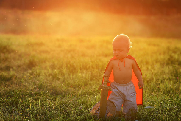 Little boy king outdoors at sunset with ray of light - Fotó, kép