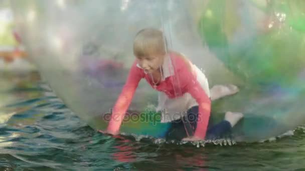 Have fun in the amusement park. Inside the transparent ball the girl runs on all fours, the ball floats in the pool - Footage, Video