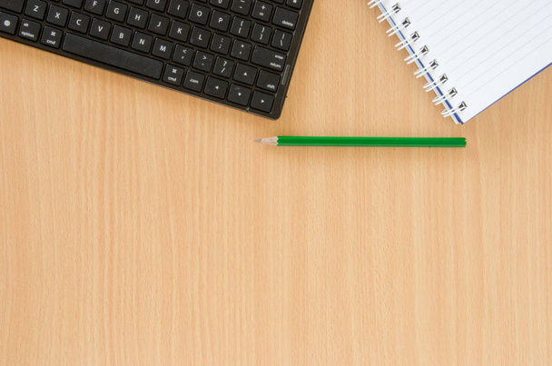 Cuaderno blanco y lápiz verde y teclado negro puestos en haya
 - Foto, Imagen