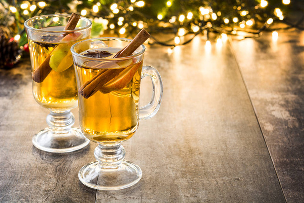 warme cider in glas, ornamenten en Kerstmis licht op houten tafel - Foto, afbeelding