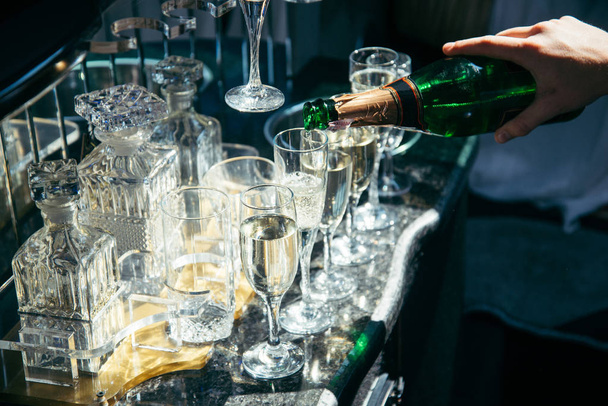 Hand halten Flasche Champagner und Gläser füllen - Foto, Bild