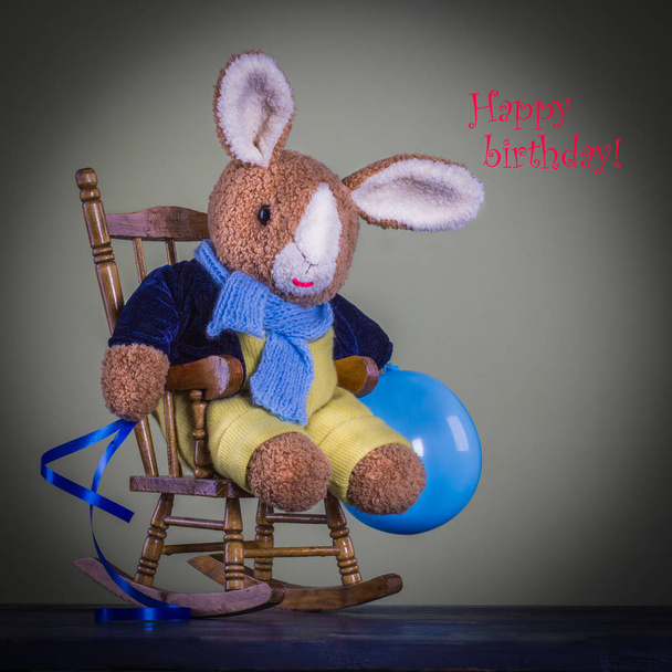 Zabawka króliczek słodki Miś z niebieskim balonem siedzieć na krześle. - Zdjęcie, obraz