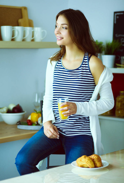 Young woman sitting near desk in the kitchen - Foto, afbeelding