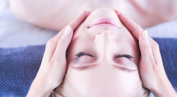 Young woman lying on a massage table,relaxing with eyes closed - 写真・画像