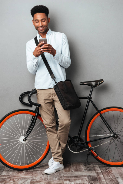 African man standing near bicycle chatting by phone. - Foto, Bild