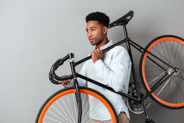 Young afro american man carrying bicycle - 写真・画像