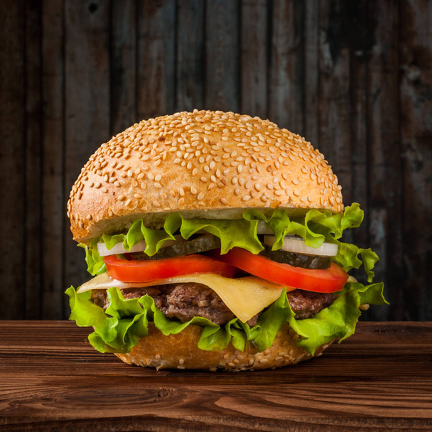 Smacznego cheeseburger z Sałatka składników na patty wołowiny z grilla na rustykalne drewniany stół z lato - Zdjęcie, obraz