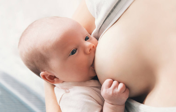 Mother breastfeeding newborn baby at home.  - Foto, afbeelding