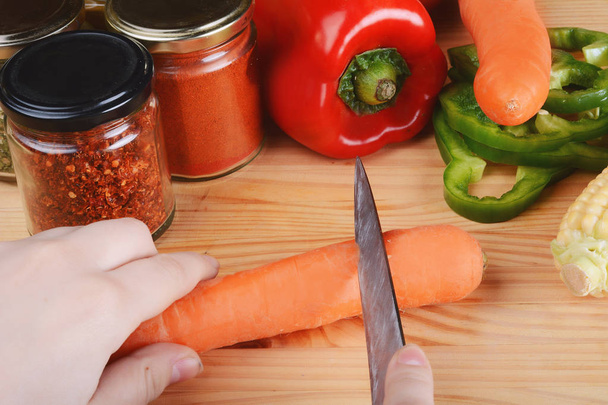 Person cutting a carrot with vegetables. - Foto, imagen