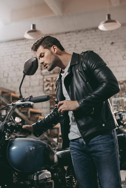 biker in leather jacket with motorcycle - Photo, Image