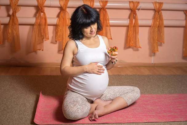 Gebelik Yoga ve Fitness kavramı. Sağlıklı annelik yaşam kavramı. küçük tahta at oyuncak ile yoga egzersiz yaparak lotus asana oturan 40 haftalık hamile orta yaşlı beyaz kadın. - Fotoğraf, Görsel