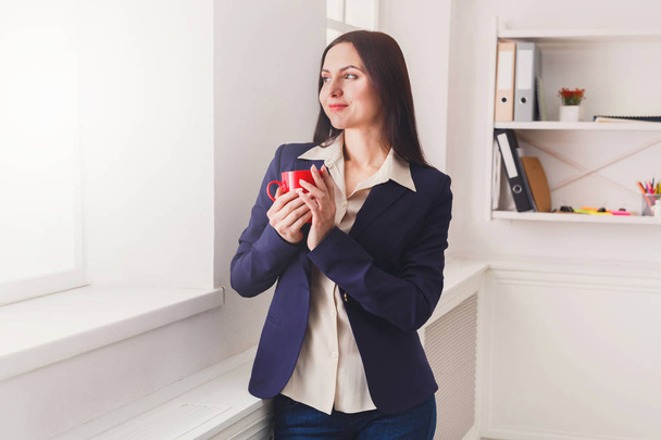 Woman drink coffee near window at workplace - Photo, Image