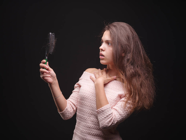 Stressed woman with hair problems on a black background. Vitamins for fragile hair. Hair treatment concept. Copy space. - Φωτογραφία, εικόνα