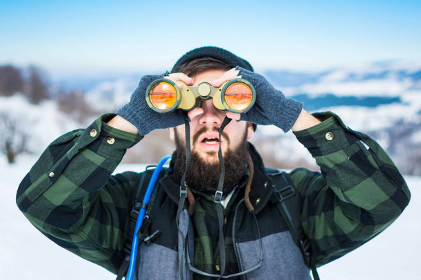 Man using binoculars on snow covered mountain - Photo, Image