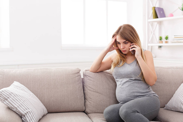 Huolestunut raskaana oleva nainen puhuu puhelimessa
 - Valokuva, kuva