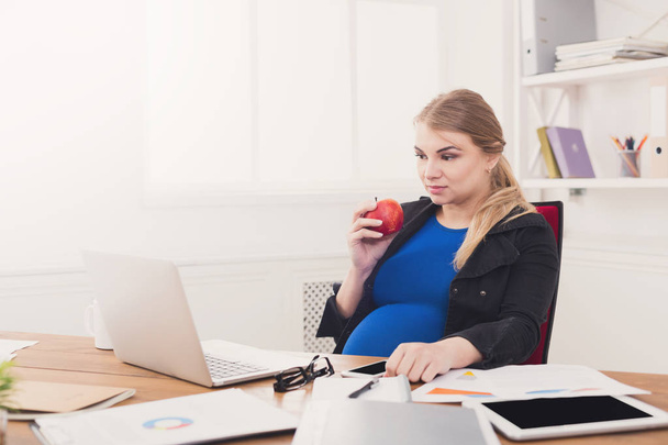 オフィス コピー スペースで妊娠中の女性の食用リンゴ - 写真・画像