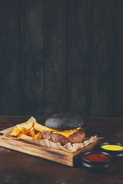 Black bun burger with potato wedges copy space - Foto, immagini