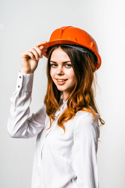 A girl in a construction helmet looks at the camera and smiles - Valokuva, kuva
