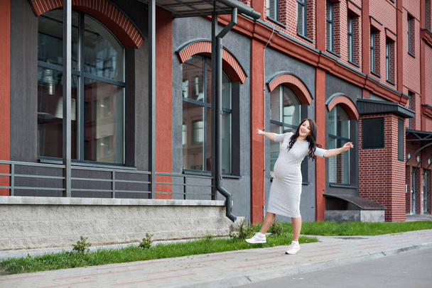  young pregnant woman walking dancing along the city windows - Photo, image