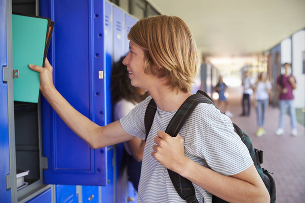 boy using locker in school corridor - Фото, изображение