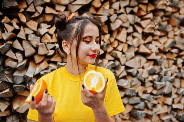 Young funny girl with bright make-up, wear on yellow shirt hold  - 写真・画像