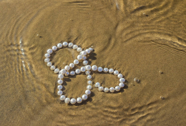 海砂の上の真珠ビーズ - 写真・画像
