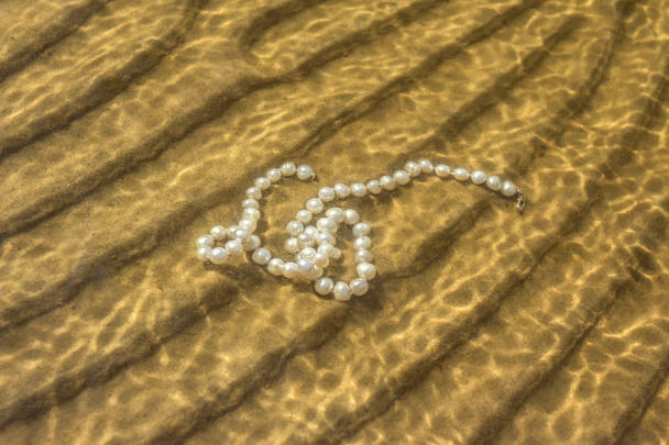 Pearl beads on the sea sand - Photo, Image