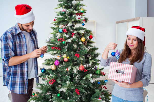 Νεαρή οικογένεια διακόσμηση χριστουγεννιάτικο δέντρο σε ευτυχισμένη περίσταση - Φωτογραφία, εικόνα