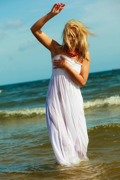 Blonde woman wearing dress walking in water - Foto, immagini