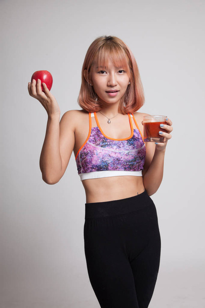 Beautiful healthy Asian girl with tomato juice and apple. - Фото, изображение