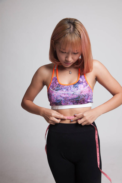 Beautiful Asian healthy girl measuring her waist. - 写真・画像