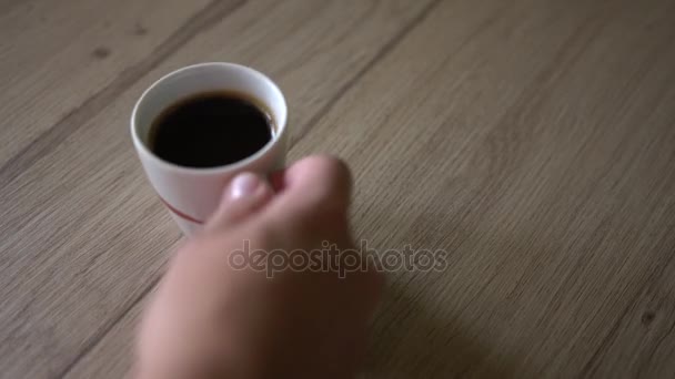 Man puts a cup of black coffe on a table. Top view - Filmati, video
