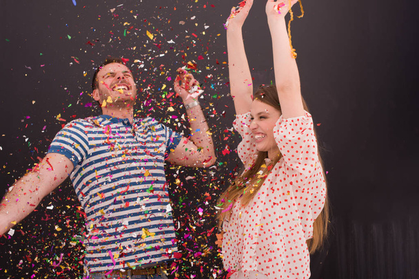 couple blowing confetti in the air isolated over gray - Foto, Bild